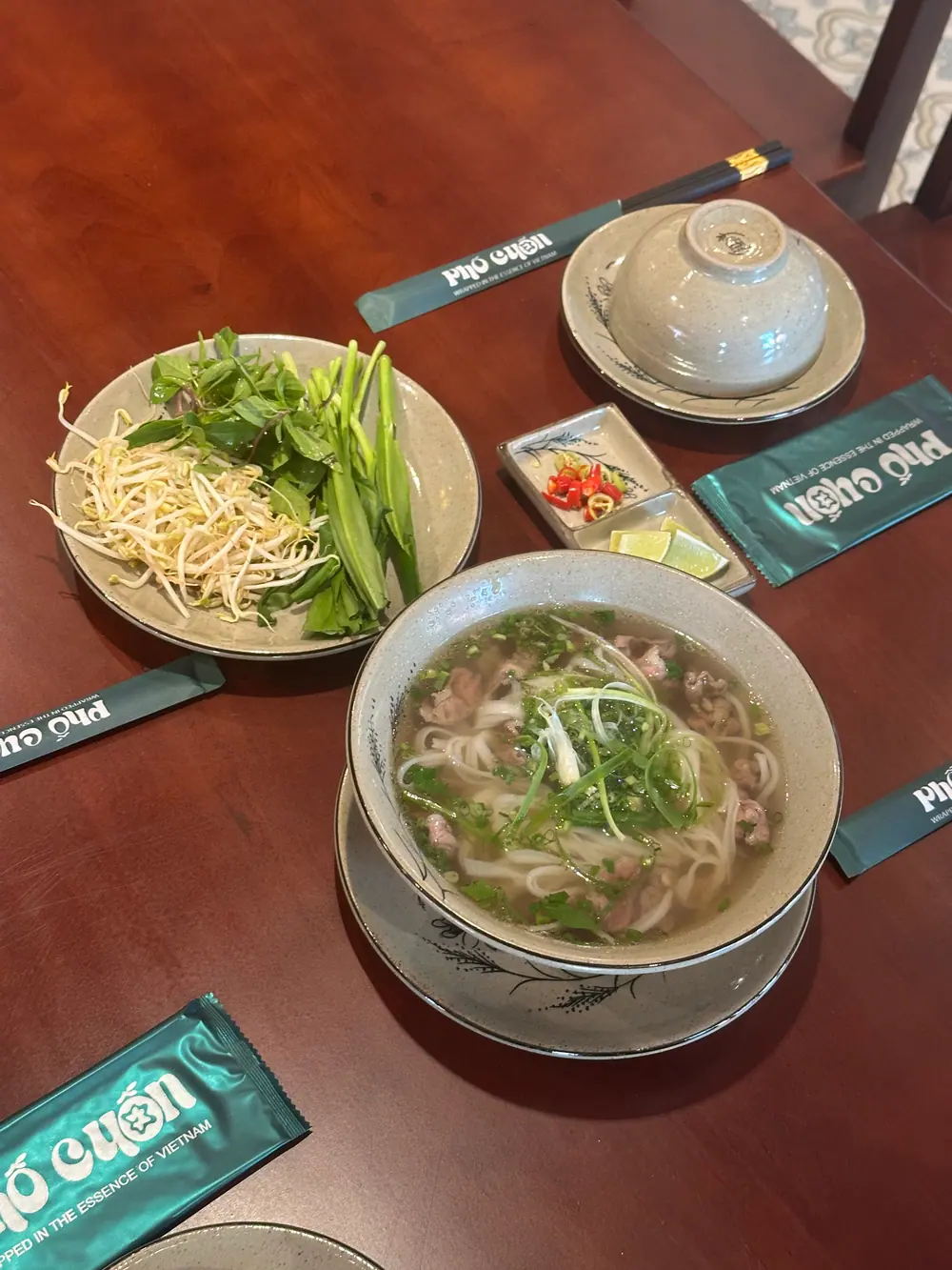 Tô phở bò nóng hổi với rau thơm bày kèm trên bàn