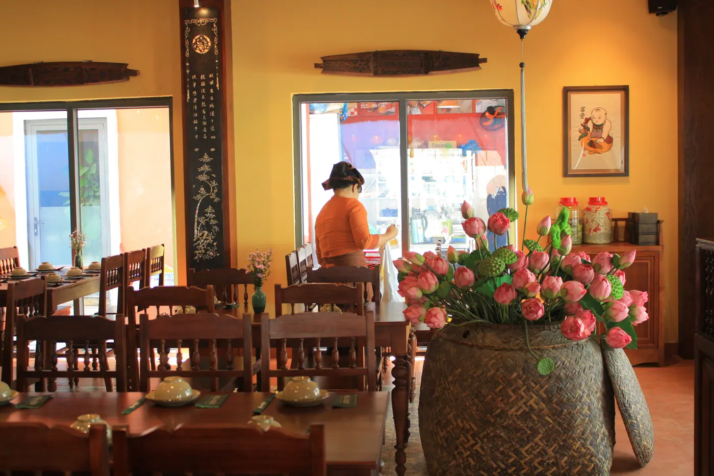 Góc phòng ăn với bàn gỗ, hoa trang trí và bảng menu treo tường