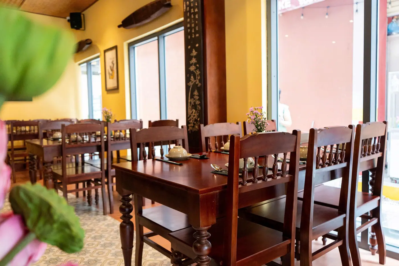 Phòng ăn nhiều bàn ghế gỗ với ánh sáng tự nhiên từ cửa sổ