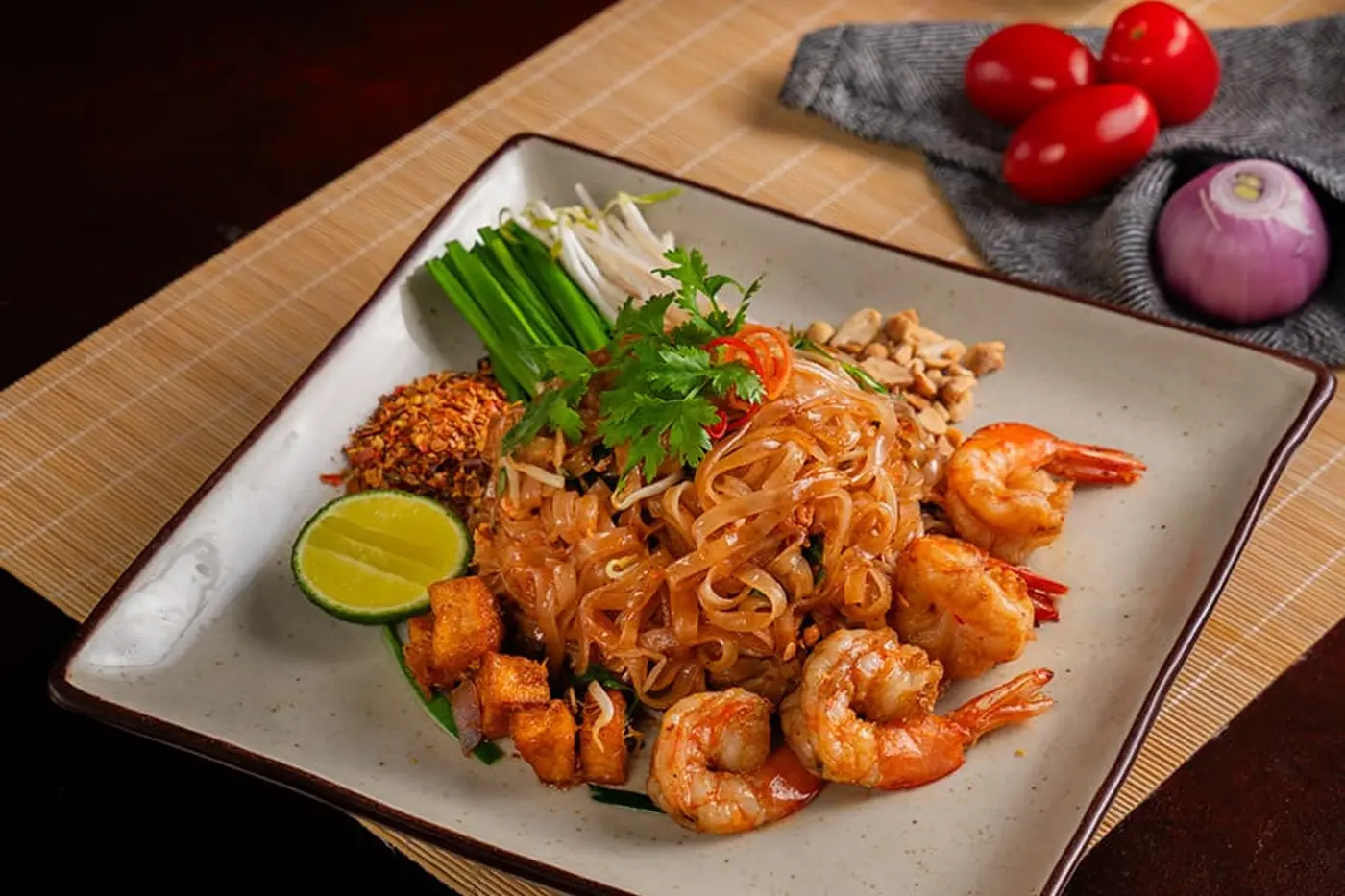 Pad thái với tôm, đậu hũ chiên, giá đỗ, hẹ, đậu phộng rang và một lát chanh